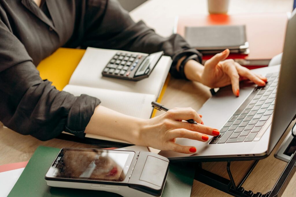 A small business owner reviewing financial data on a laptop, with a digital calculator interface visible, symbolizing the use of business finance calculators.