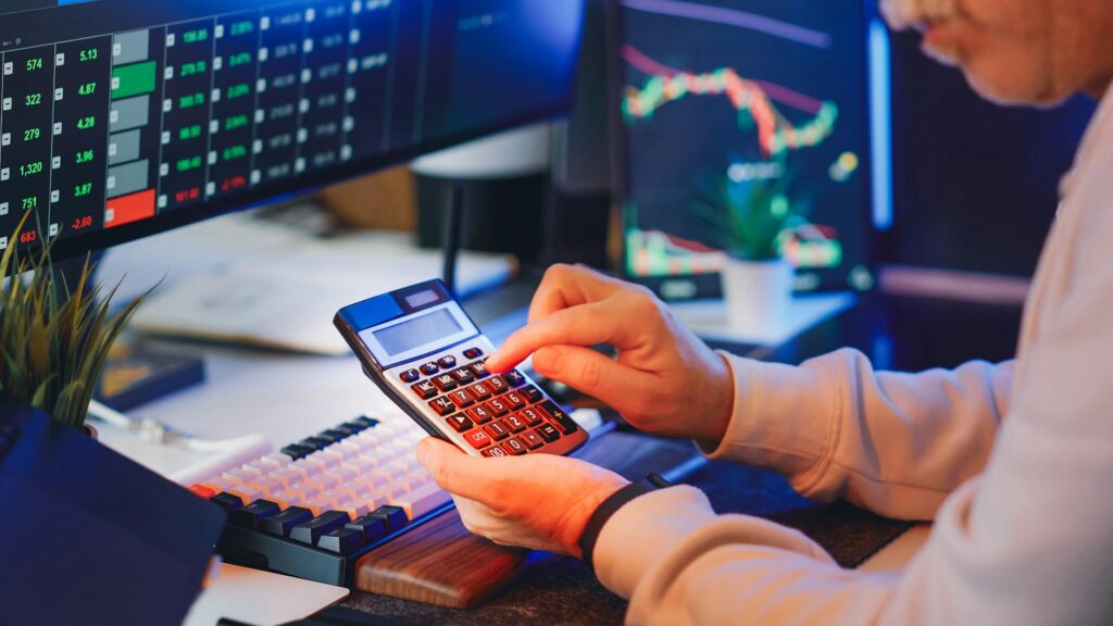 A calculator displaying profit figures with business charts in the background, illustrating business profit margin calculation.