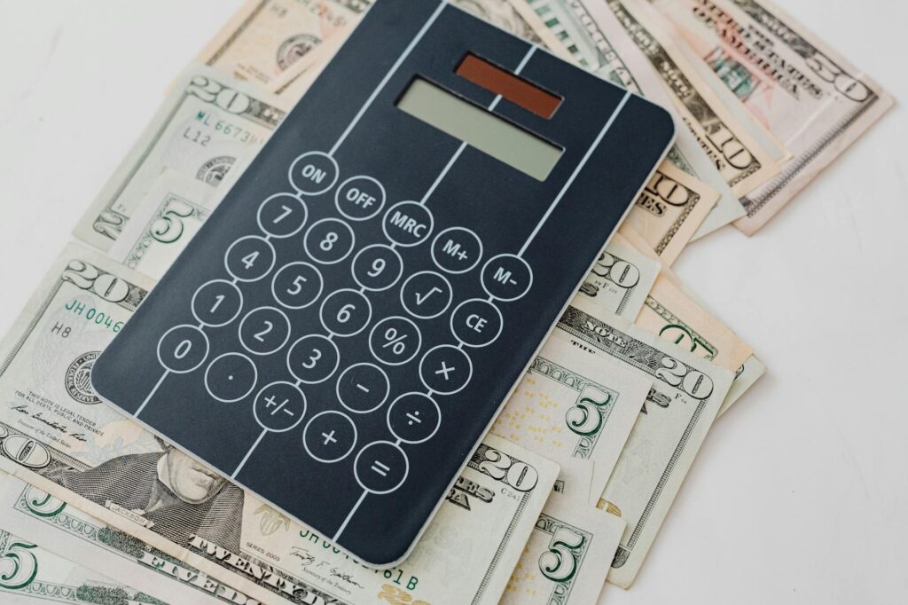 Hand using an emergency fund calculator on a laptop with charts and savings icons, symbolizing financial planning and security.