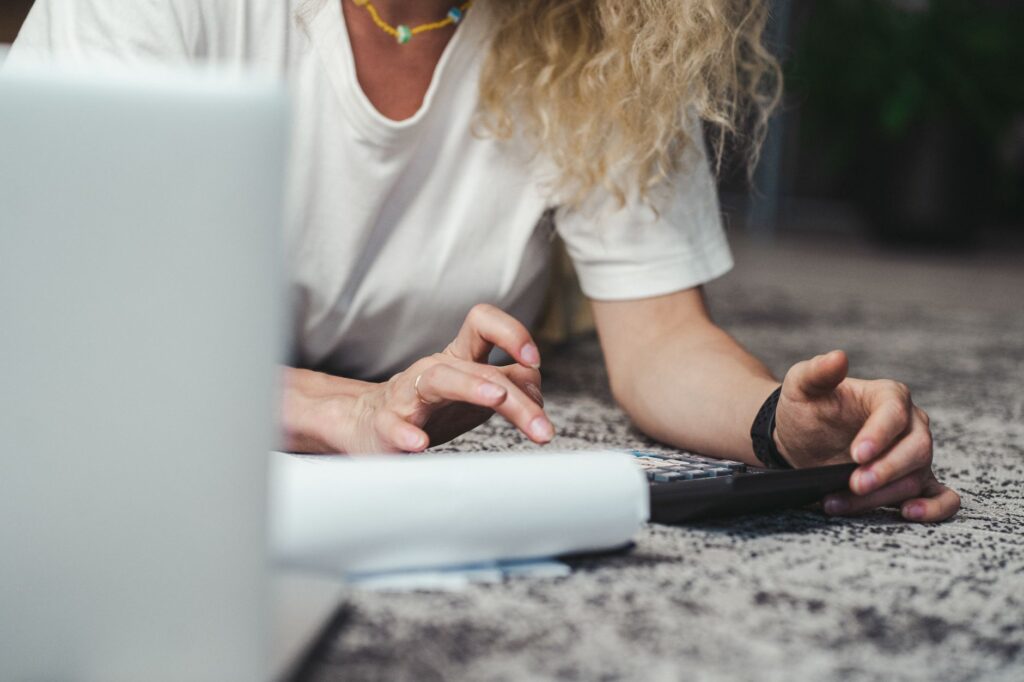 A freelancer using an hourly rate calculator on a laptop, surrounded by notes and a coffee cup, symbolizing careful financial planning.