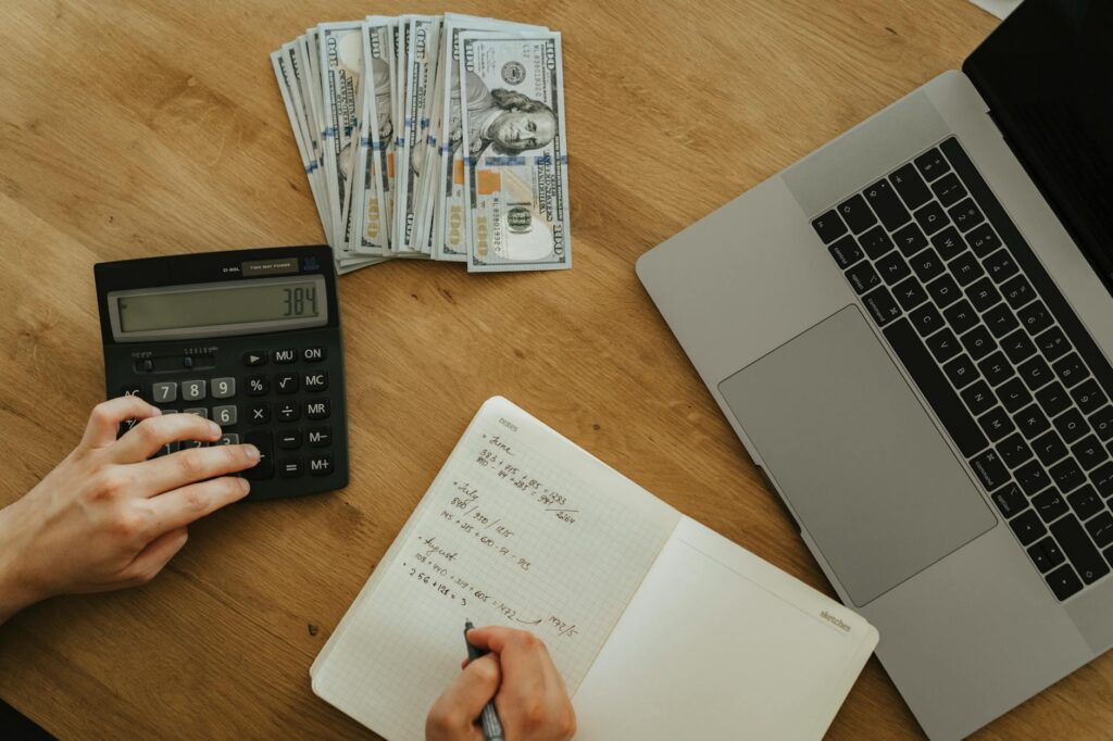 A person diligently calculating their net worth using a net worth calculator on a laptop, surrounded by financial documents and a calculator, symbolizing financial planning and wealth management.