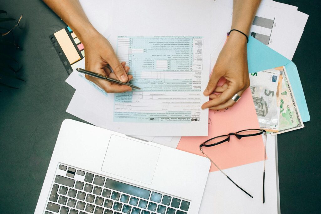 A person using a tax refund calculator on a laptop, surrounded by tax documents and a physical calculator, illustrating how to calculate tax refunds easily.