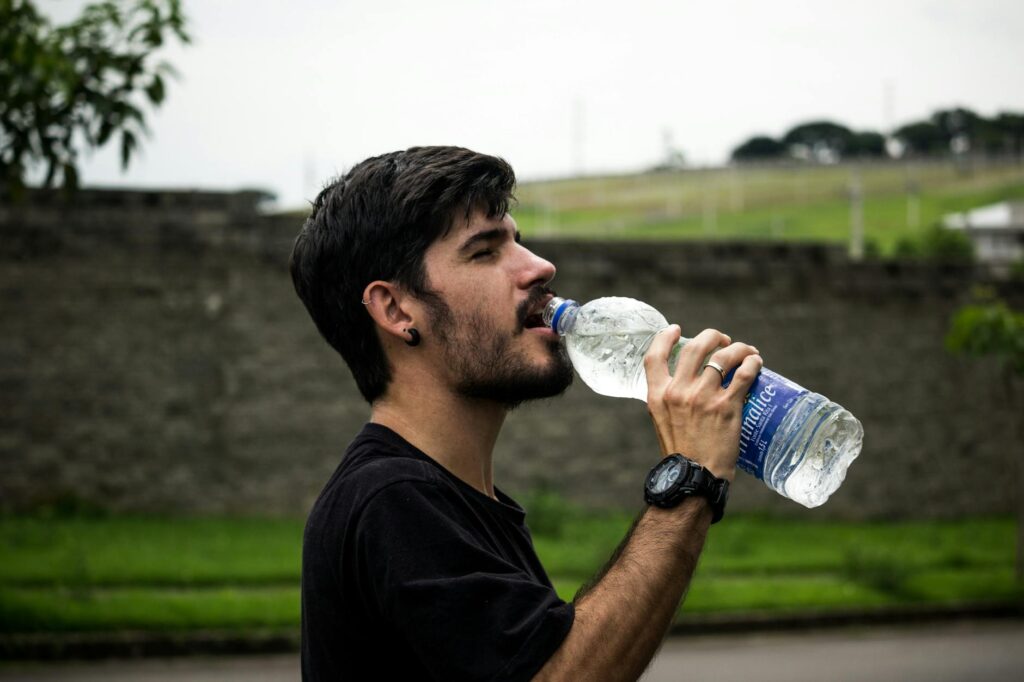 A person taking a refreshing sip of water from a reusable bottle, symbolizing healthy hydration and a commitment to wellness.