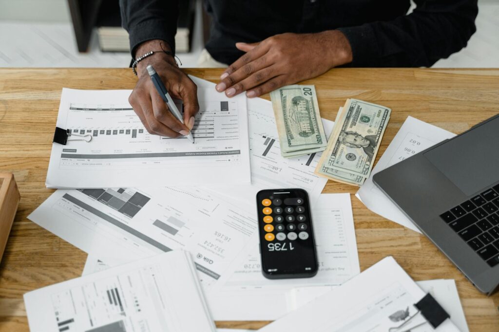Person using a monthly expense planner and budgeting calculator to manage personal finances